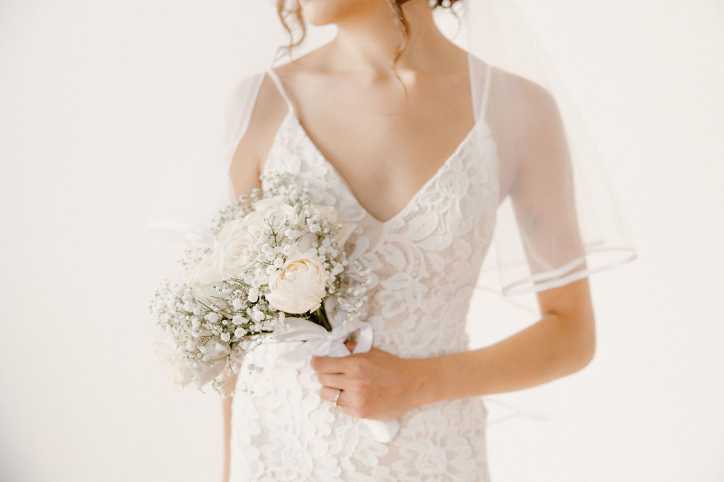 Bride holding bouquet of flowers white dress Vanessa with Complete Weddings + Events Omaha wedding photographer