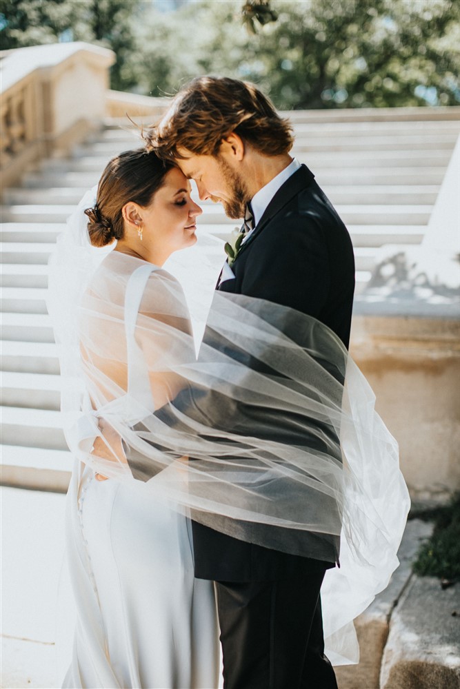 Bride and groom with the veil wrapped around at The Leo Ballroom in Omaha NE with photographer Katie Hammond