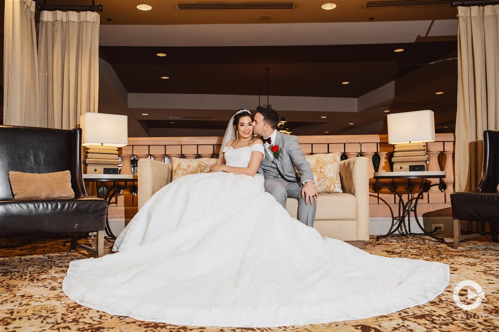 Late November bride and groom kissing bride's dress train spread across floor