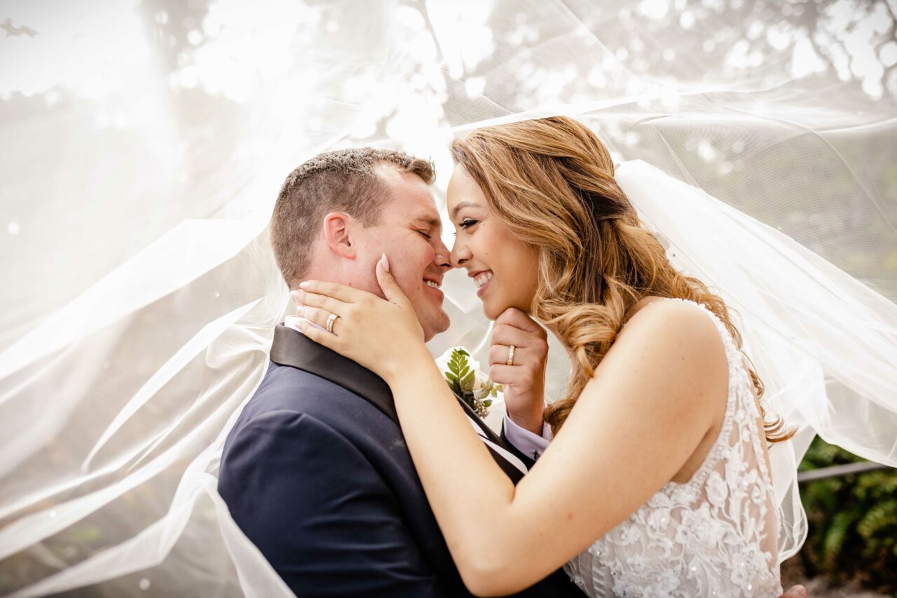 Couple kissing in Orlando, Florida after their ceremony while bride's veil drapes over them