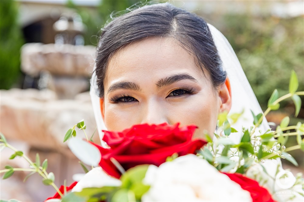 Bride with a red rose in front of her face colorful wedding photo during November wedding