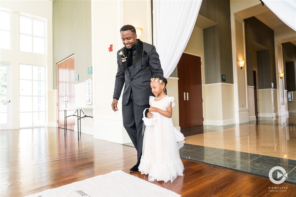 Groom walking flower girl down the isle at Lake Mary Events Center Fall wedding