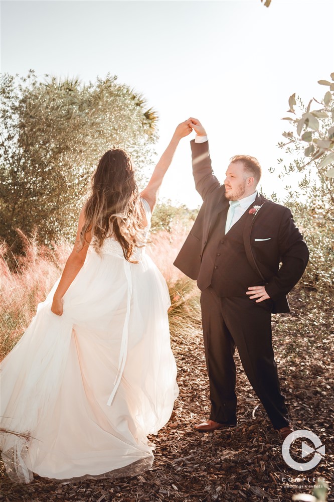 Bride and groom dancing while sun peeks through the back of the photo during Fall small weddings