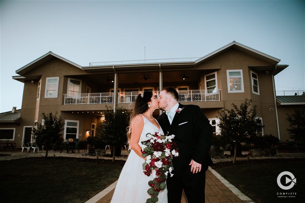 Bride and groom kissing at Island Grove Winery during couple's wedding day showing off venue