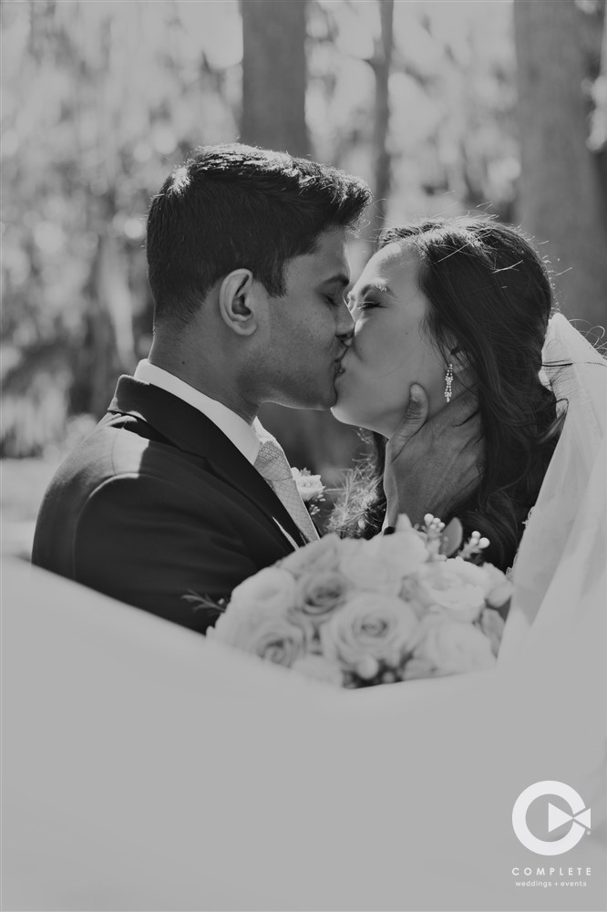 Couple kissing black and white photo two shooter wedding during outdoor photo shoot at wedding ceremony
