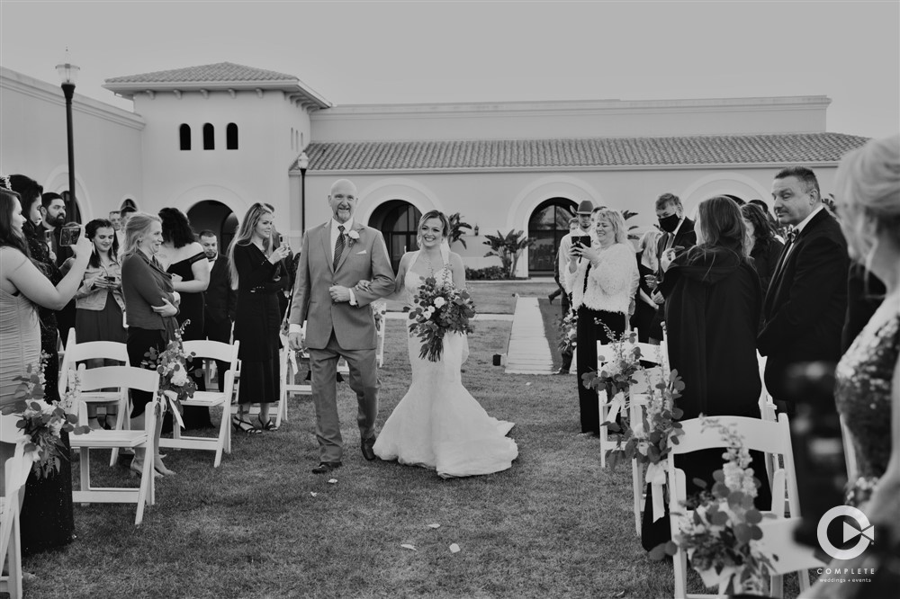Black and white photo of bride being escorted down the isle by her father at Lake Mary Events Center