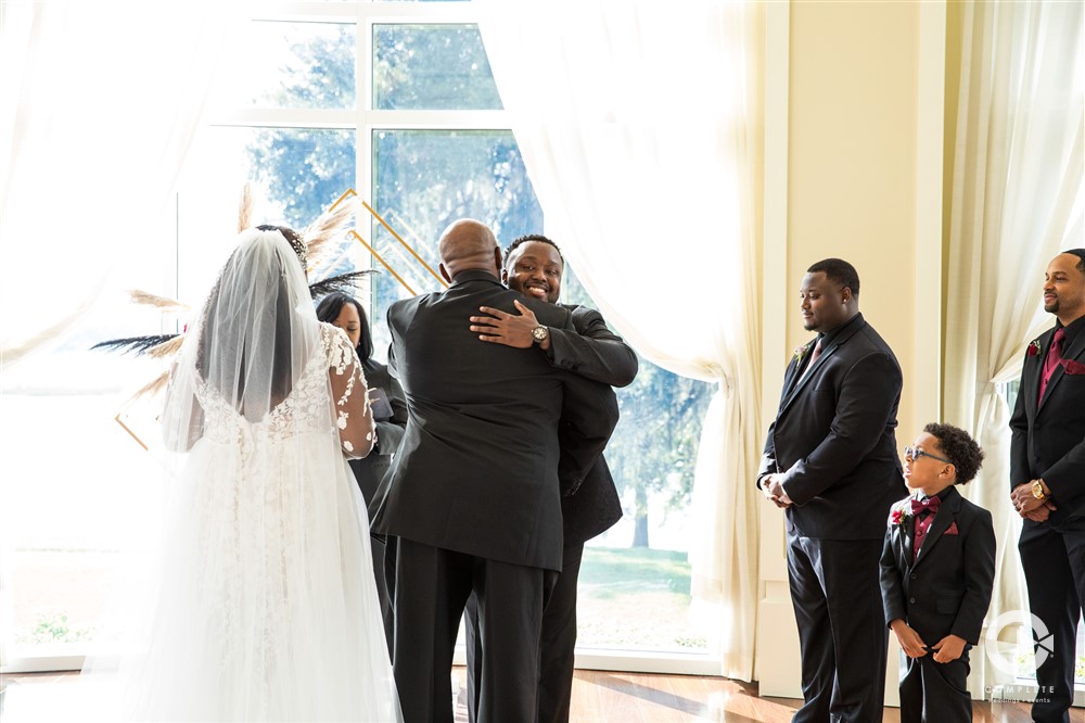 Lake Mary Event Center wedding ceremony groom hugging the father of the bride at the altar