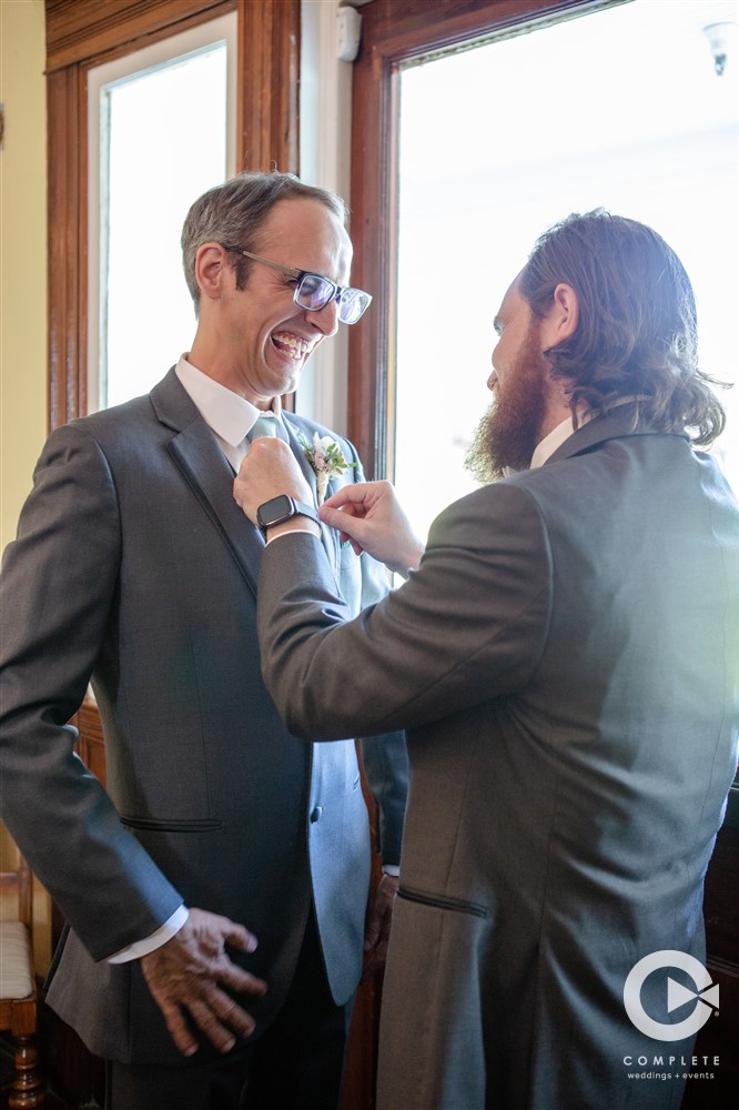 Groom putting his bow tie tied up for him by his best man at a Highland Manor wedding