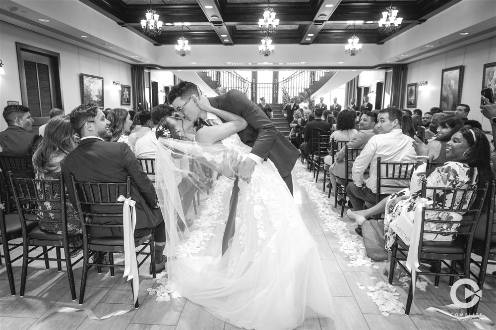 Bride and groom kissing at the end of the altar black and white shots