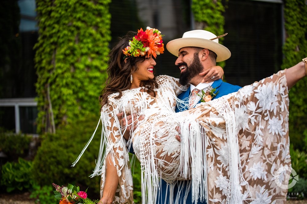 Wedding couple groom holding his bride during a tropical themed wedding