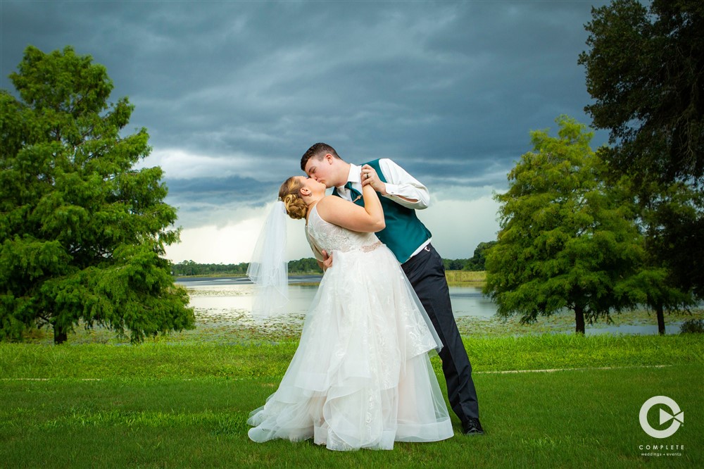 Bride and groom kissing under the rain clouds at their Lake Mary Event Center wedding