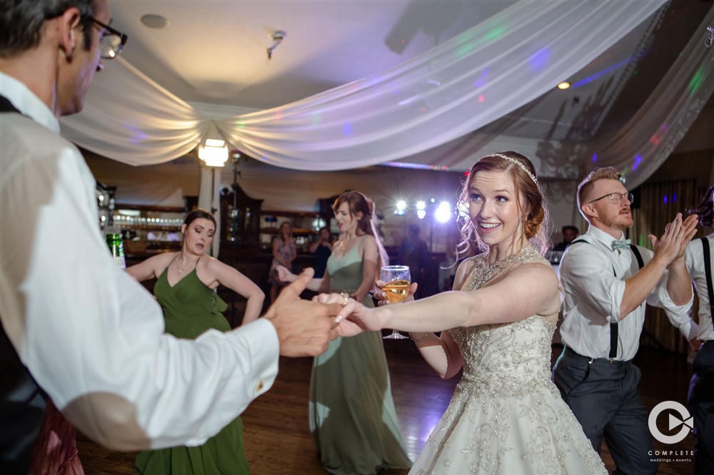 Bride dancing at her reception at The Highland Manor taking groom's hand