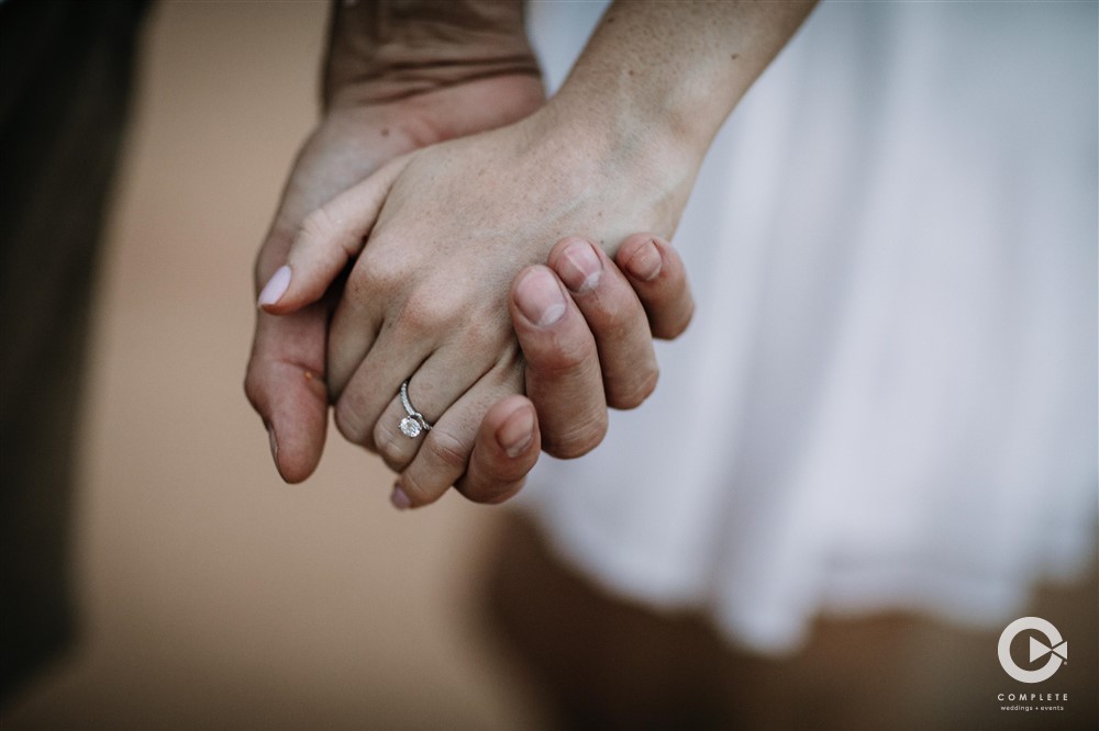 Couple holding hands with engagement ring blinging