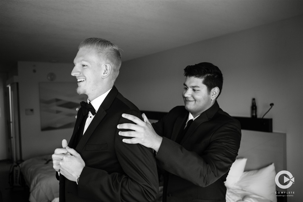 Groom putting on jacket black and white photo during getting ready at Garden Villa