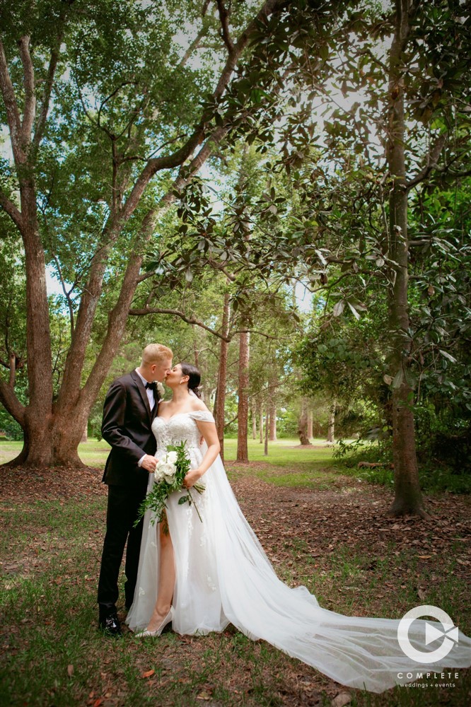 Bride and groom kissing at The Garden Villa very green background