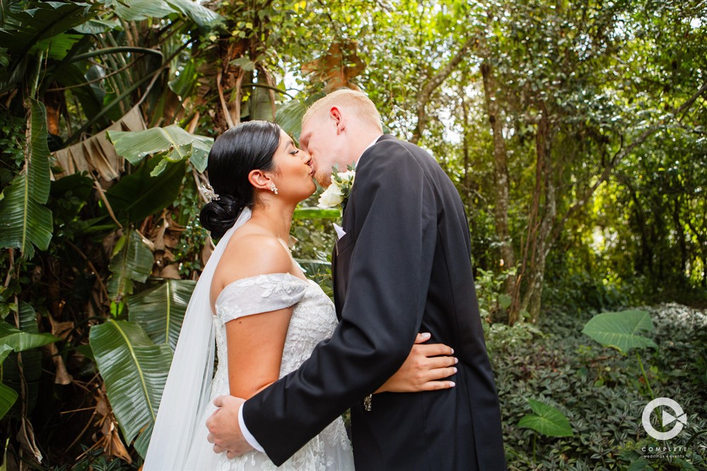 Bride and groom kissing with greenery in the background at The Garden Villa in October