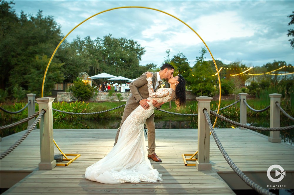 Groom dips bride and kisses her on a dock during October wedding reception