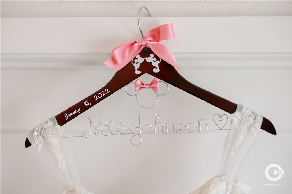 Bride's wedding dress on a hanger with her name etched into the hanger 2022 wedding