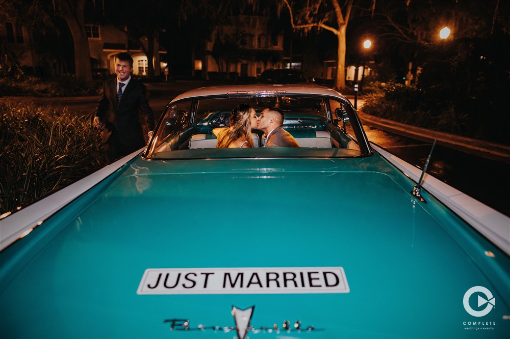 Just married sign on a car as they kiss and head out of the reception site