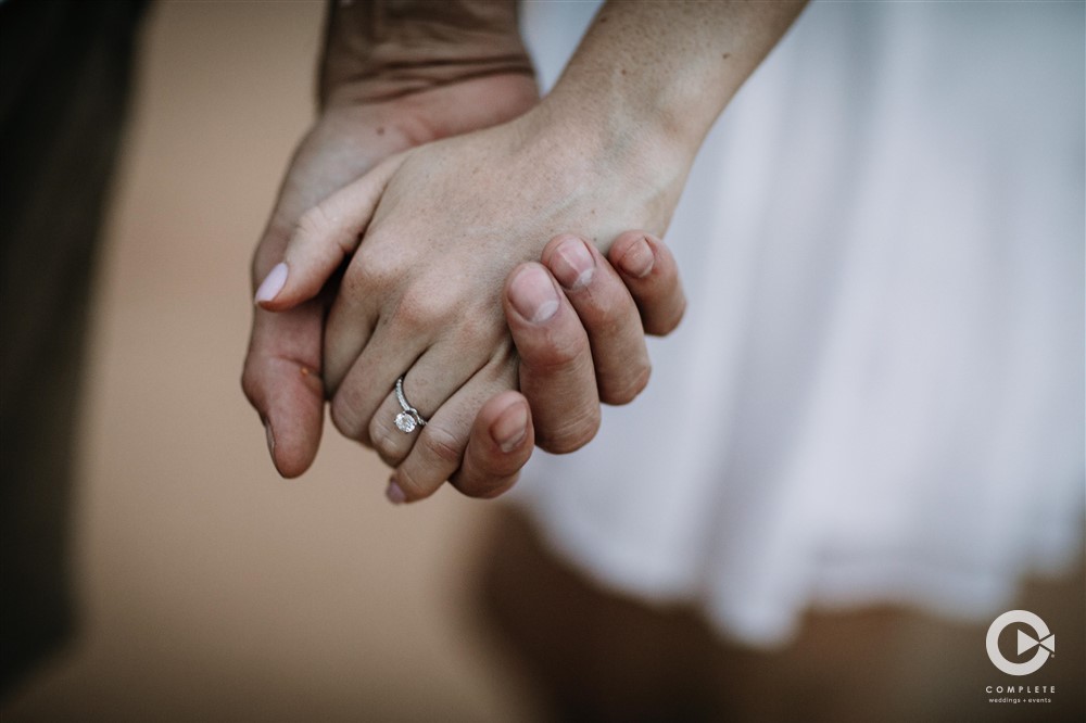 Couple holding hands while engagement ring showing in photo