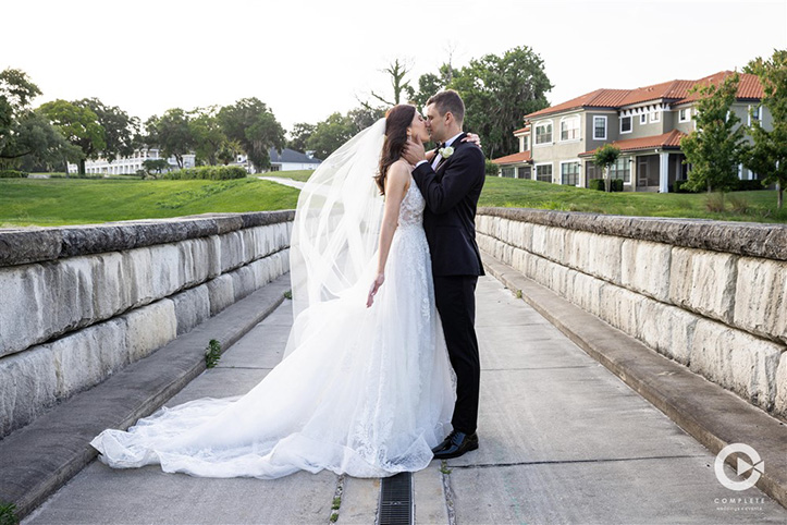Bride and groom share a kiss on a bridge at Tuscawilla Country Club