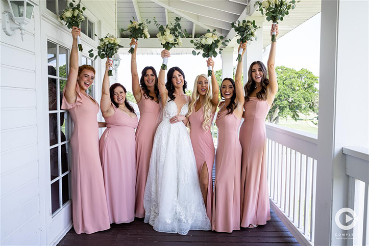 Bride and her bridesmaids have fun holding their bouquets at Orlando, FL wedding