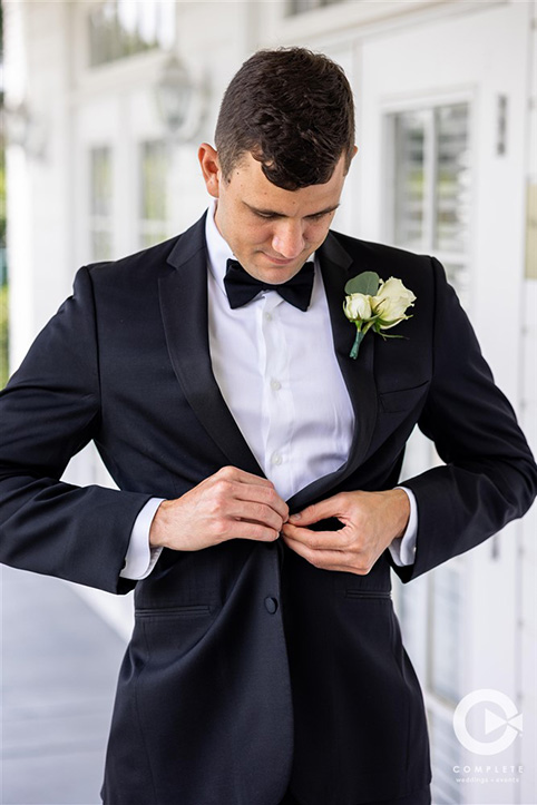 Groom buttoning up his jacket at Tuscawilla Country Club in Orlando, FL