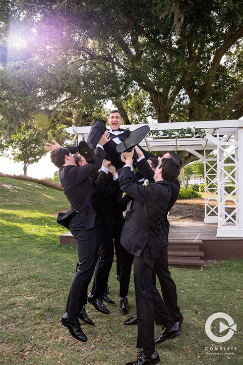 Groomsmen throwing groom and having fun at Tuscawilla Country Club