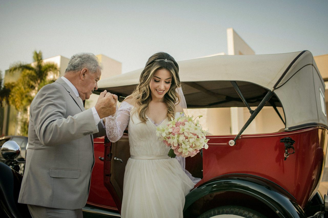 Bride getting help out of her classic car during her wedding