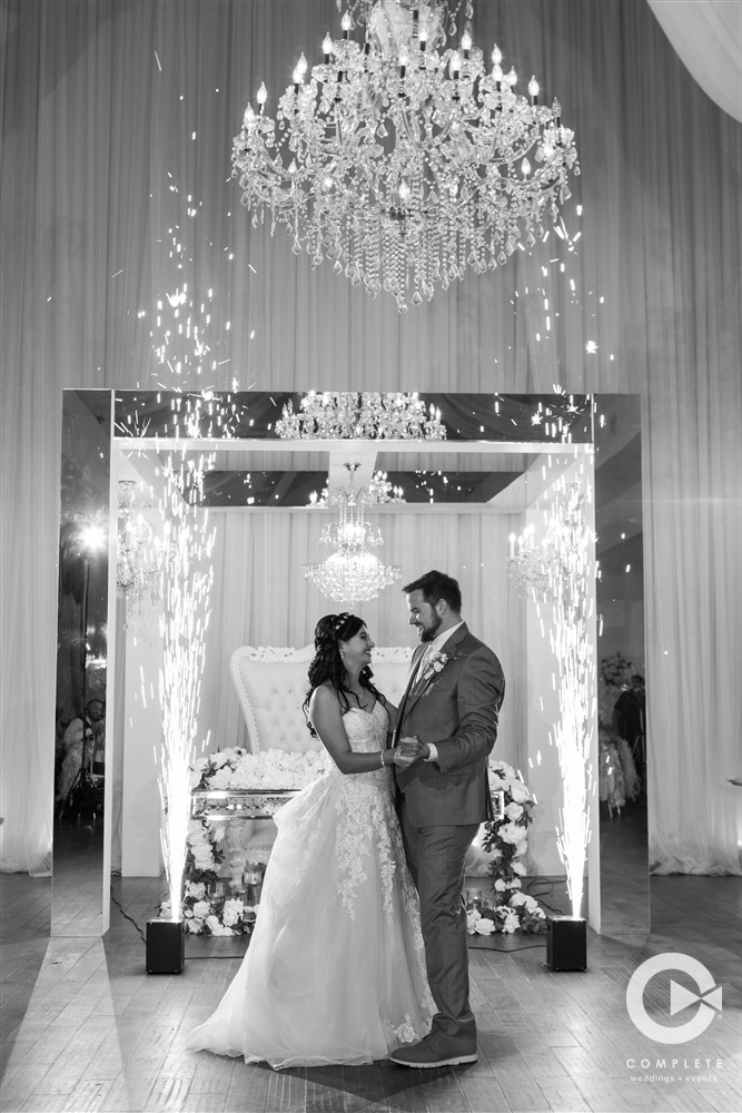 Bride and groom dancing with beautiful chandelier overhead cold sparks going off behind them.