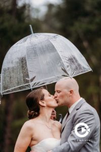 bride and groom kissing in the rain