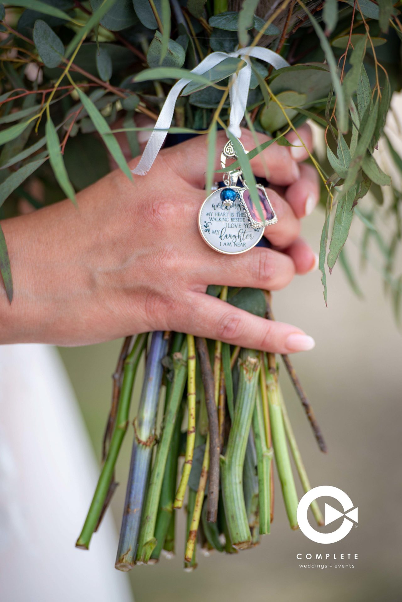 bride holding bouquet with a special medalion