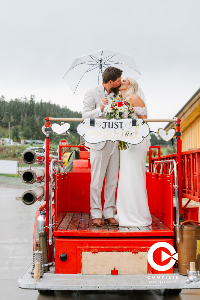 Bride and groom kissing on the back of a fire truck