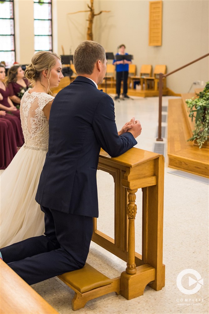Bride and groom kneel at altar