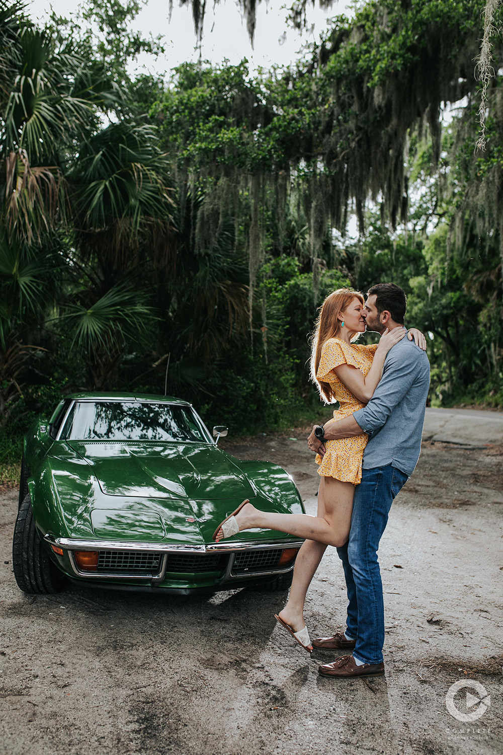 engaged couple kiss in front of green car