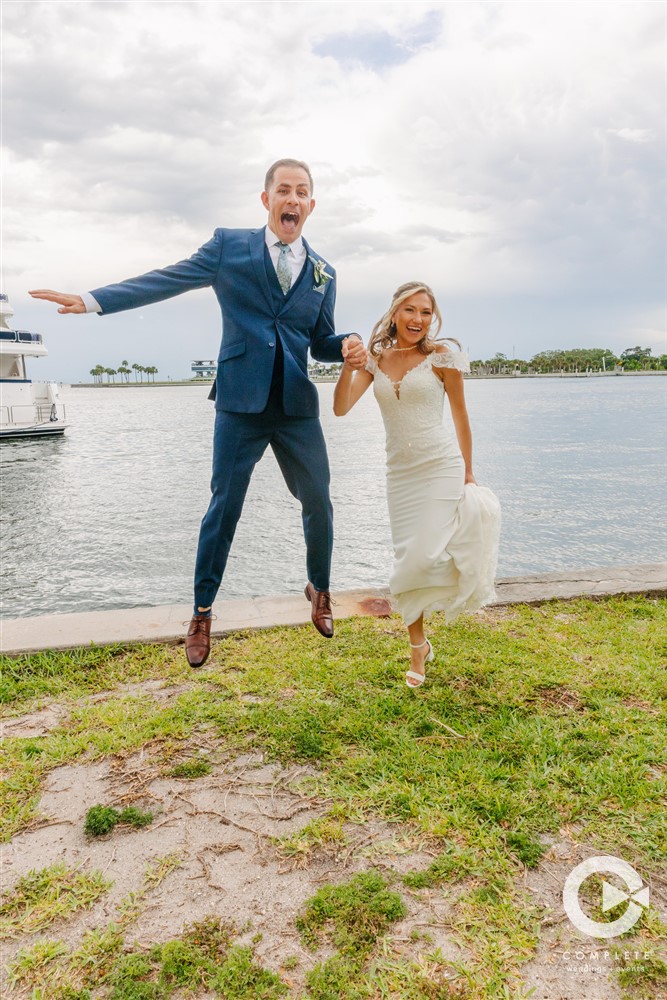 Bride and groom leap in air hand in hand