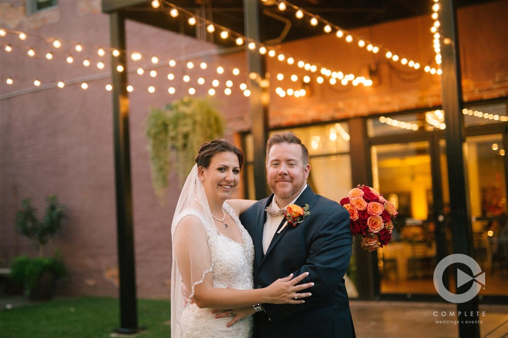 Tracy & Patrick Couples Portrait on Wedding Day in Savoy Ballroom Courtyard with Twinkle Lights in Background