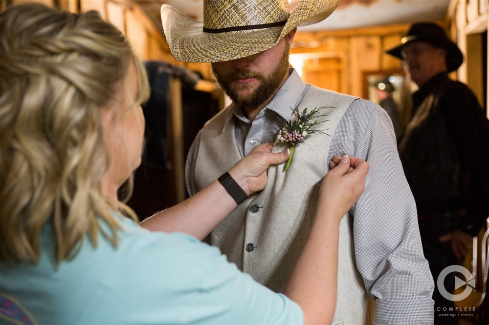 mother of groom putting on grooms boutonniere
