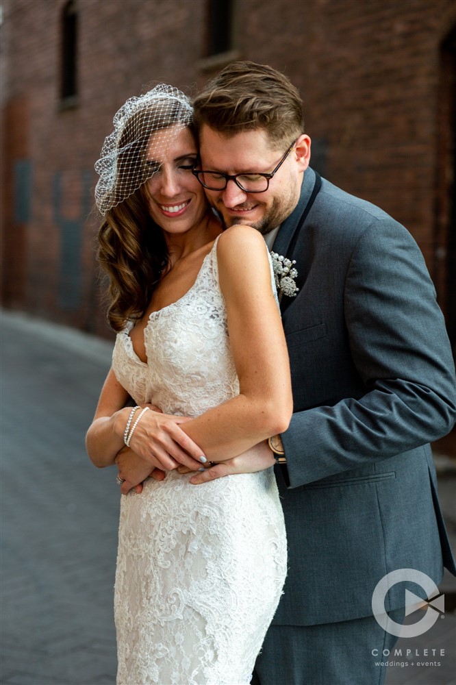 candid hug of bride and groom in an industrial background