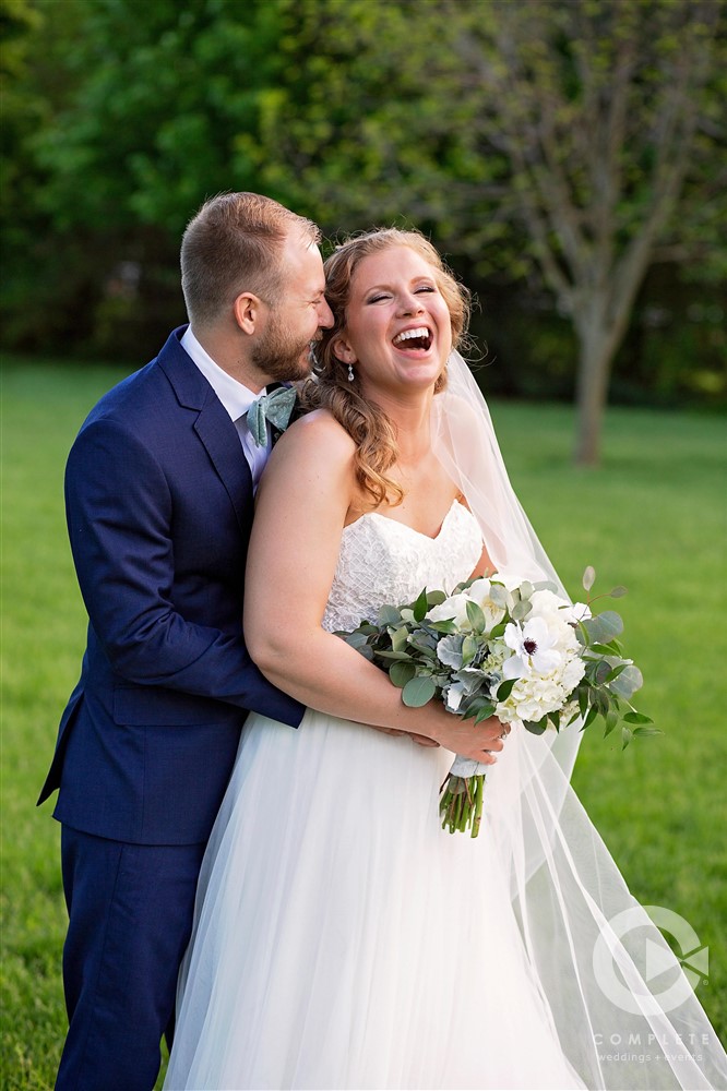 Groom whispering into brides ear and giving a huge laugh