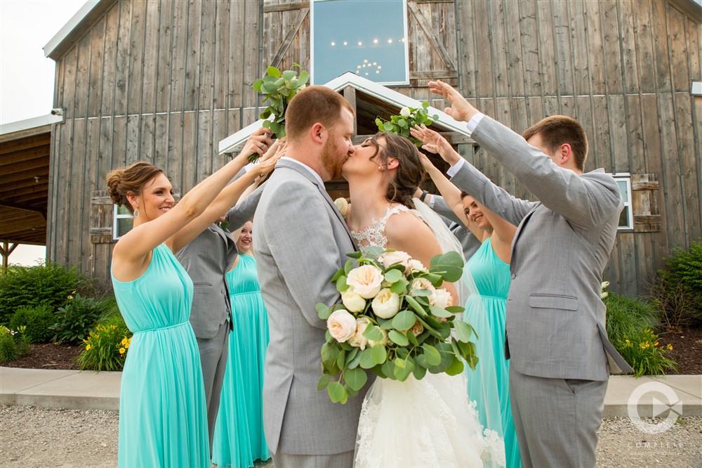 bride and groom kissing beneath hand of bridal party