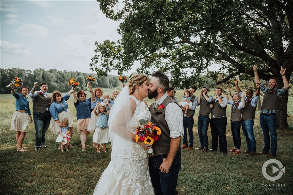 bride and groom kiss in front of bridal party