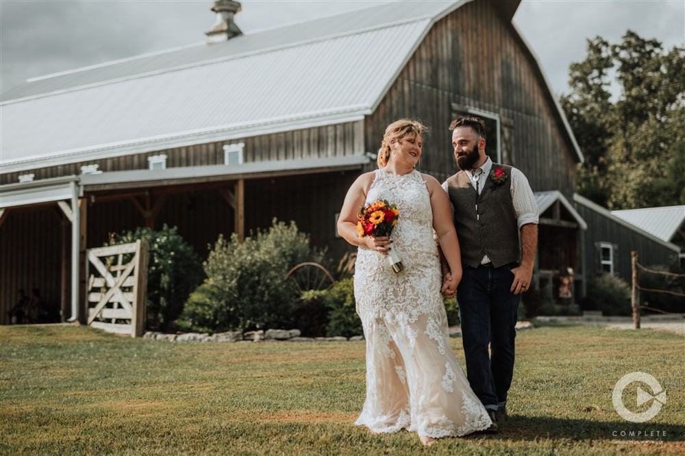 bride and groom holding hands in front of gambrel barn