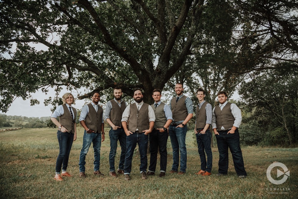 groomsmen and groom hang out under a tree