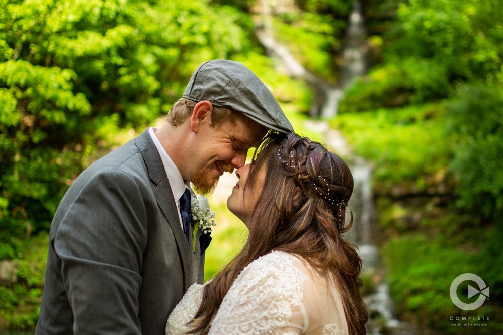 Katie + Brandon bride and groom boop noses in front of waterfall