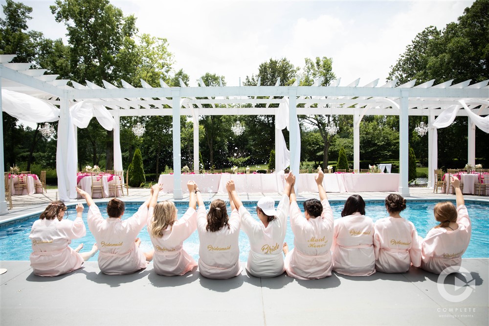 Nichole & Lonnie bridal party in robes at pool haseltine estates