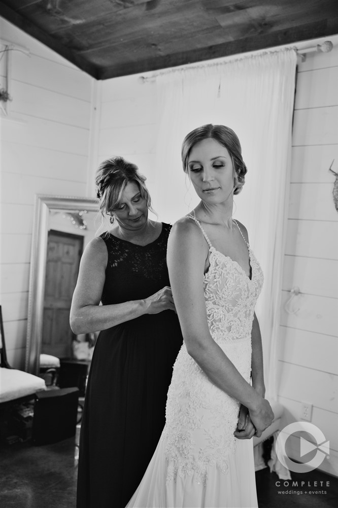 bride being buttoned up before ceremony