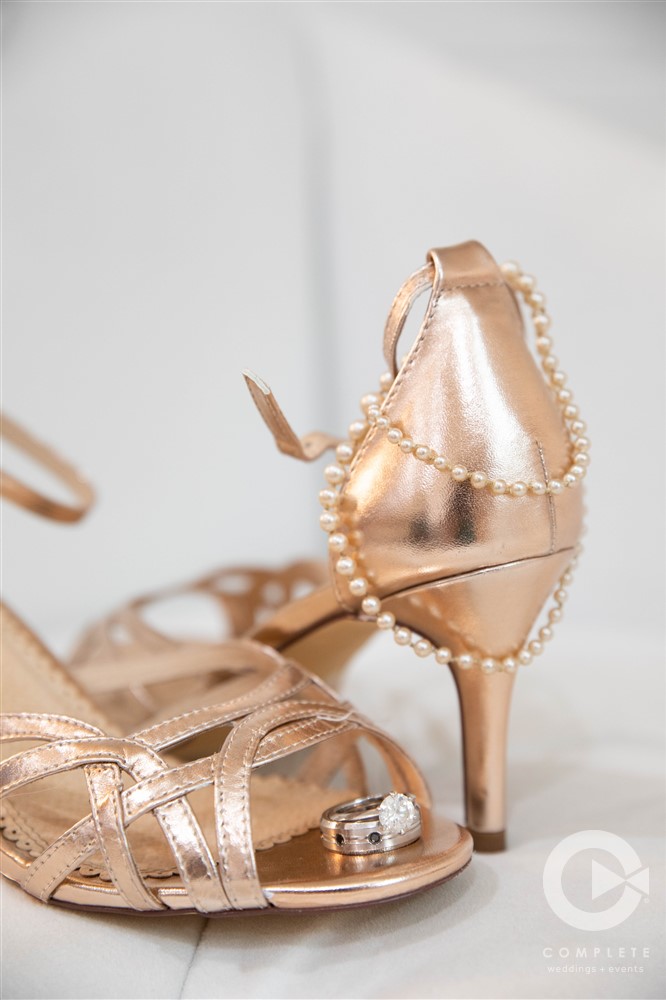 wedding rings on bride's gold shoes