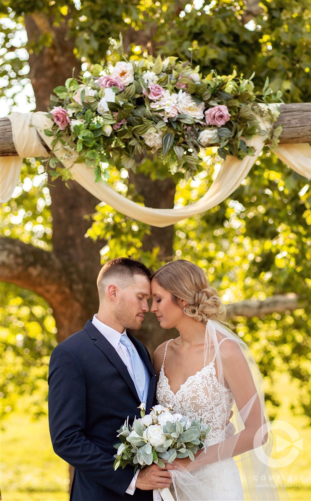 bride and groom bump heads under trellis