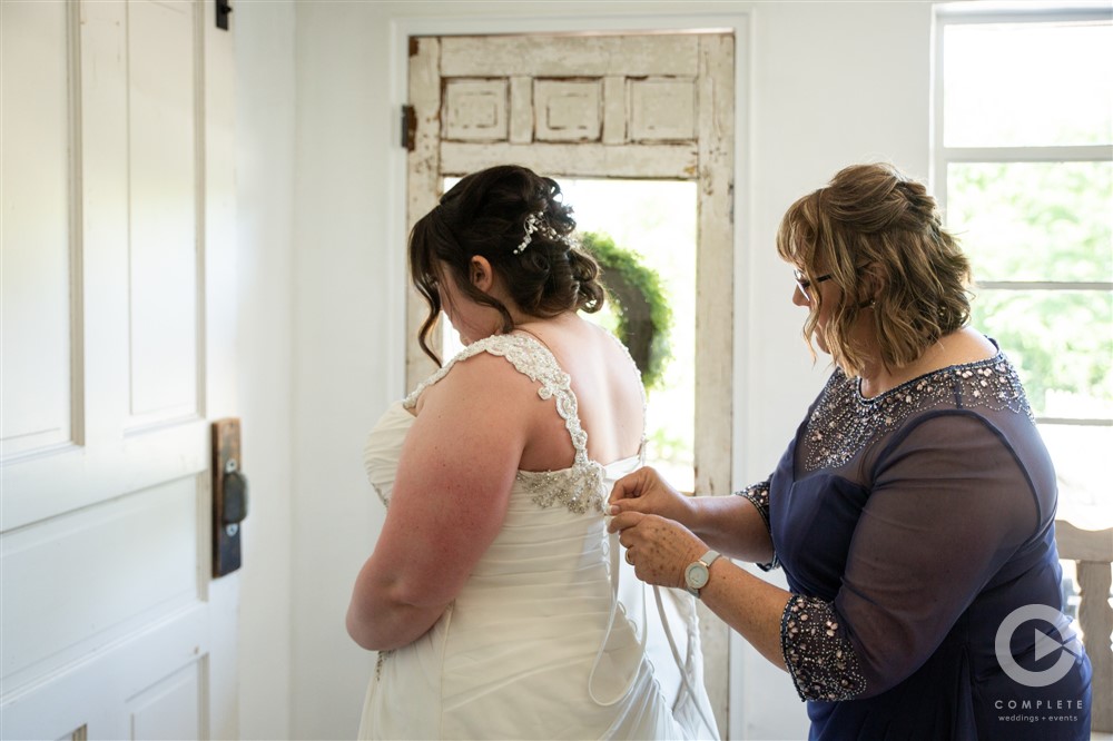 bride having her dress laced in preparation for ceremony